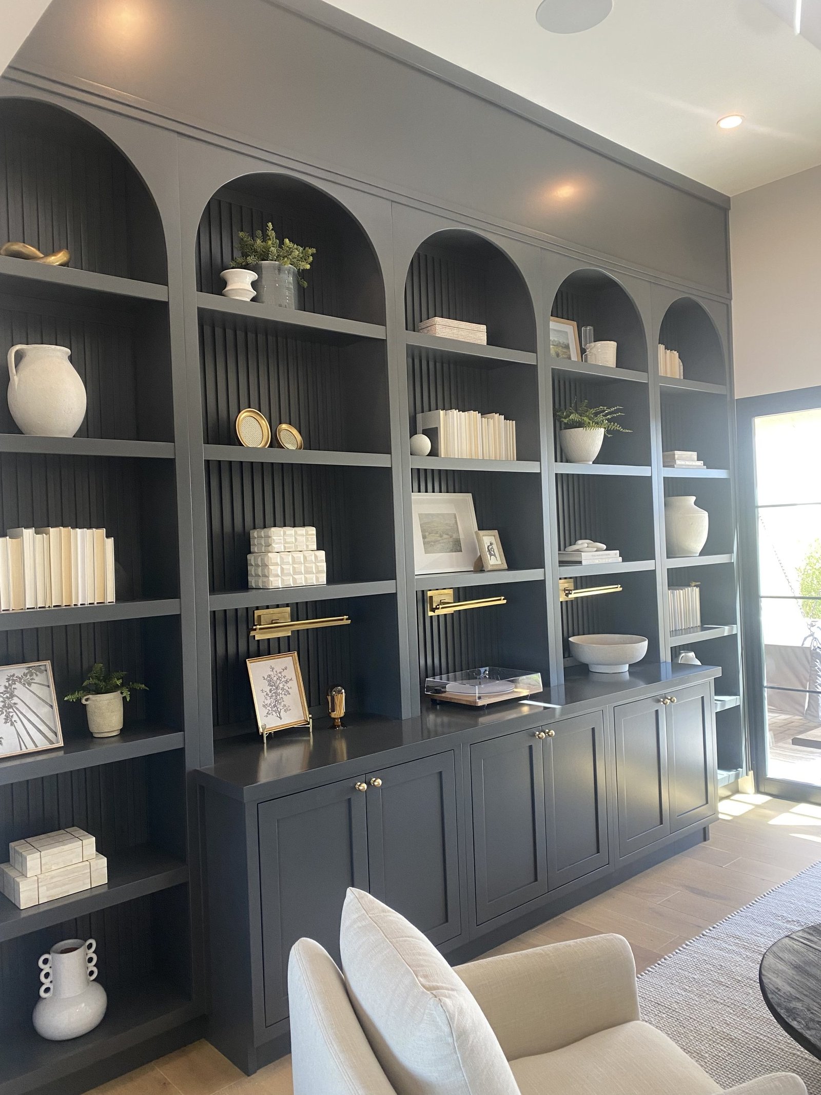 Arched charcoal built-in shelving with brass lights