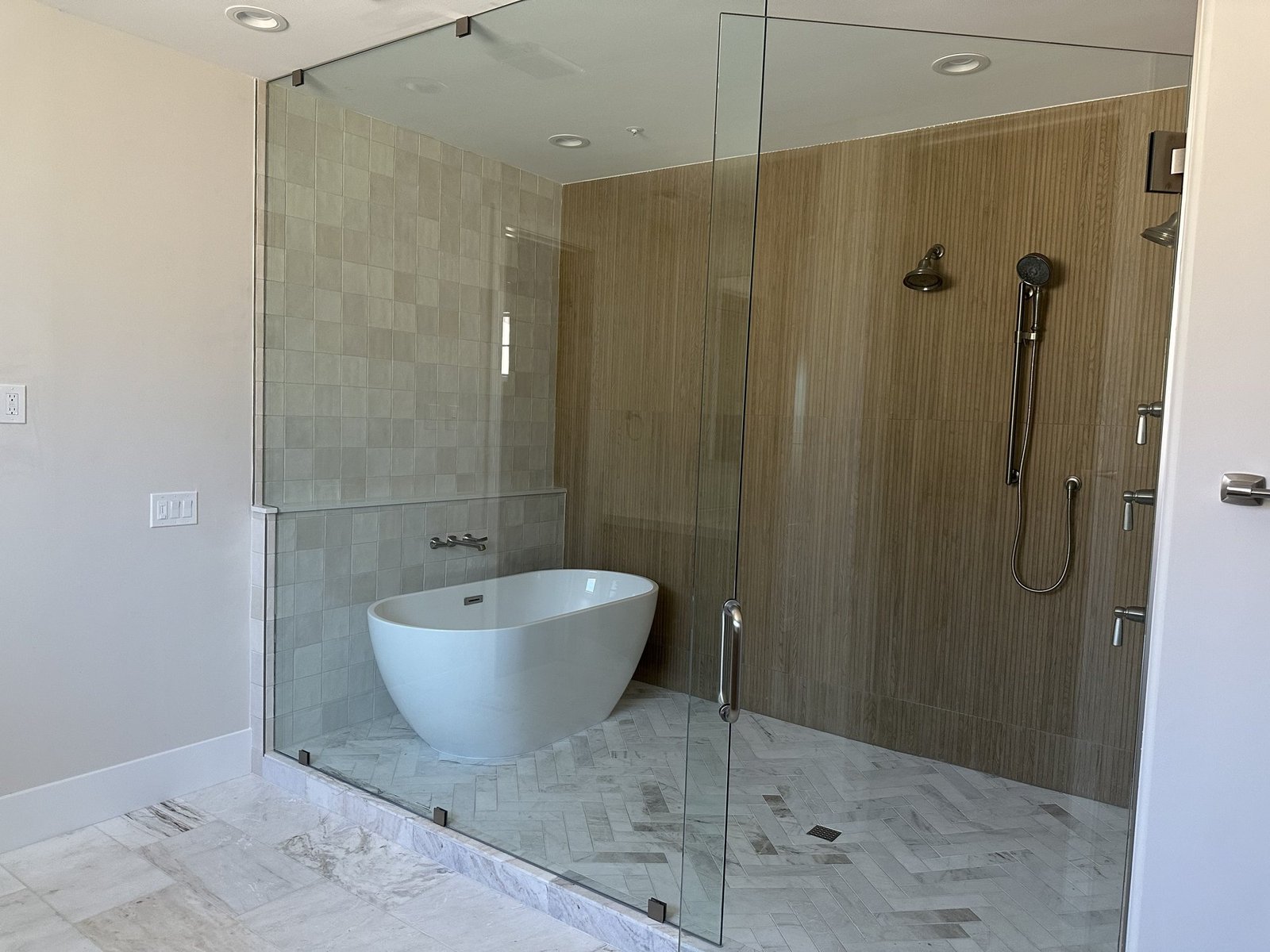 Wet room bath with freestanding tub and herringbone marble